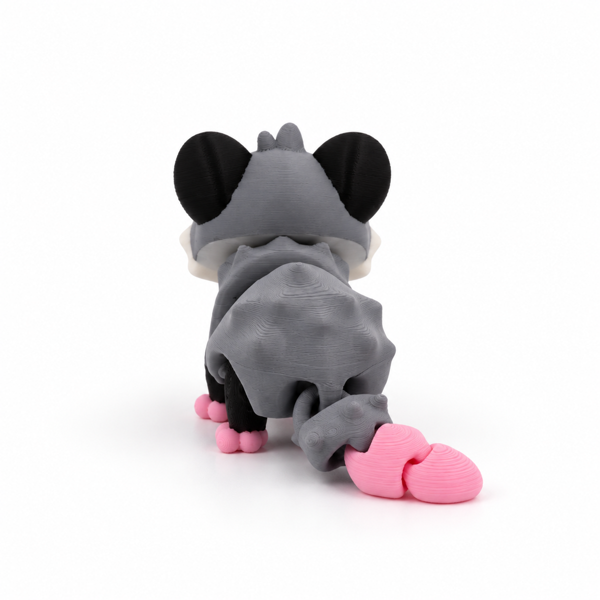 Figurine opossum grise et rose imprimée en 3D dans une forêt